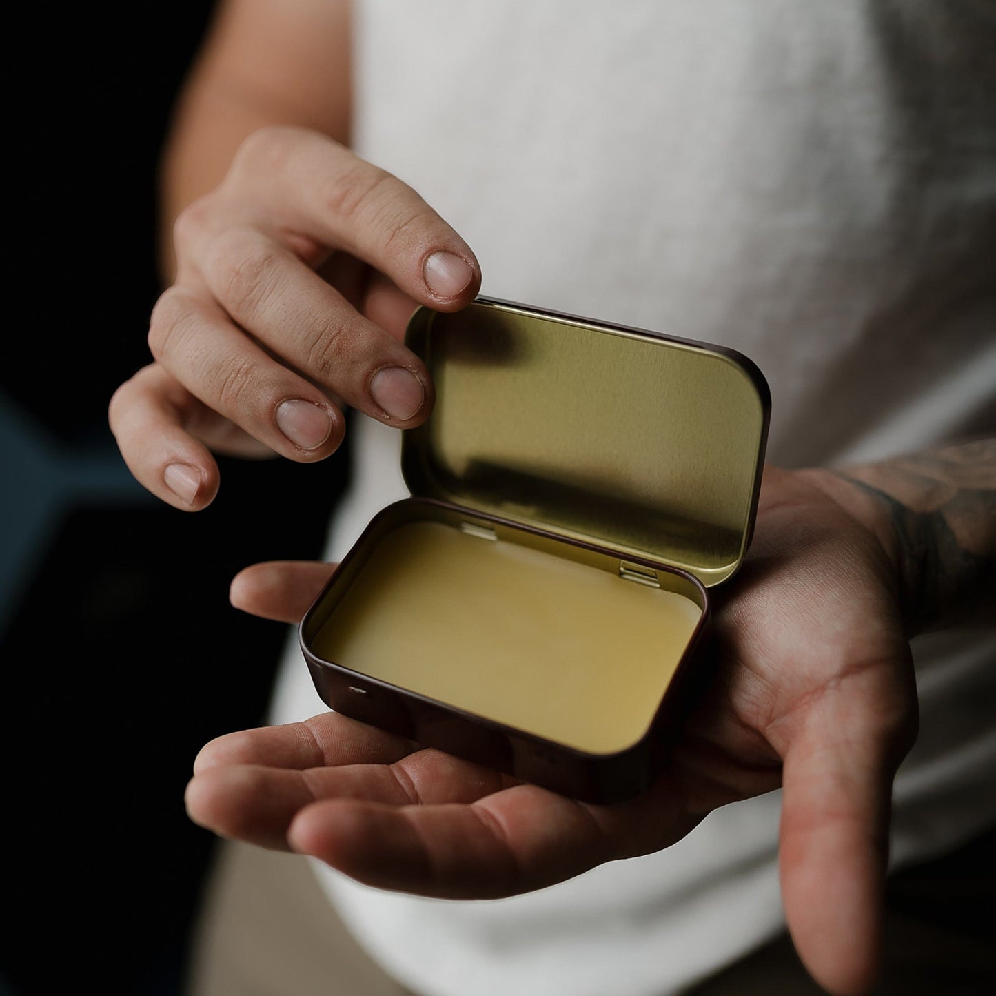 Open Warlord solid cologne tin held in hands showing balm texture - Photograph