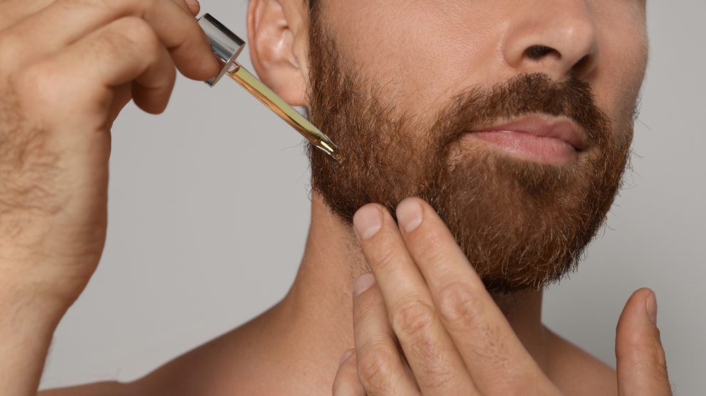 Man applying beard oil to a full beard as part of his daily beard care routine.
