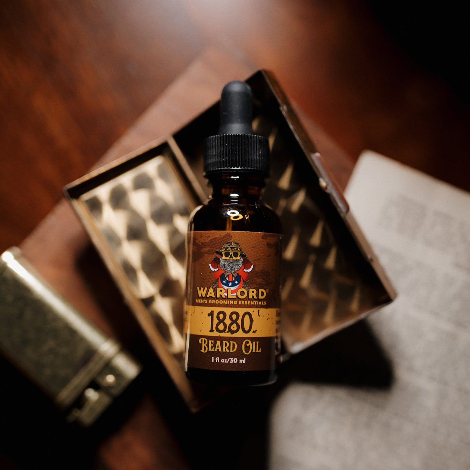 Warlord 1880 Beard Oil bottle displayed in a vintage box with a lighter and open book – premium beard oil for men’s grooming, classic masculine style.