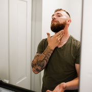 Man applying Warlord Shave Lotion to neck in bathroom mirror shaving - Photograph