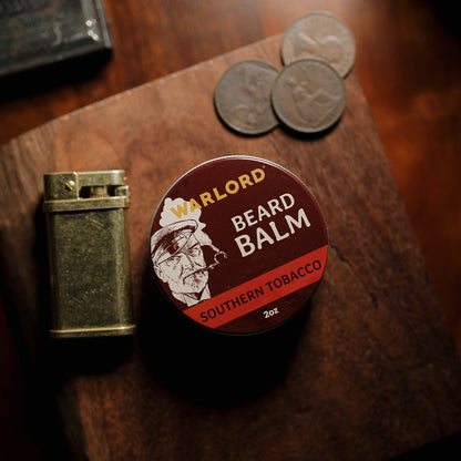Warlord Southern Tobacco Beard Balm tin on rustic wood with vintage lighter and old coins – premium beard balm for men, classic masculine grooming.